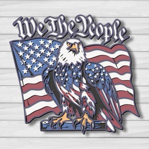 Op de afbeelding: Een patriottisch ontwerp met een Amerikaanse zeearend, de Amerikaanse vlag en de tekst "We The People". De adelaar is afgebeeld met gedetailleerde veren in rood, wit en blauw. De vlag heeft rode en witte strepen en een blauw veld met witte sterren.