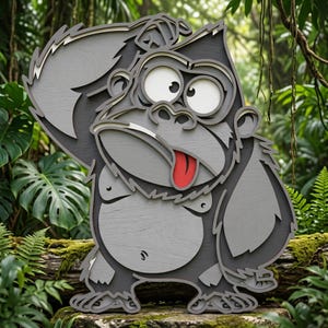 Könnte beinhalten: Ein mehrschichtiges Wandkunstobjekt aus Holz, das einen Cartoon-Gorilla mit weit aufgerissenen Augen und herausgestreckter roter Zunge darstellt. Der Gorilla ist in Grautönen mit sichtbarer Holzmaserung gehalten und zeigt einen verspielten Gesichtsausdruck.