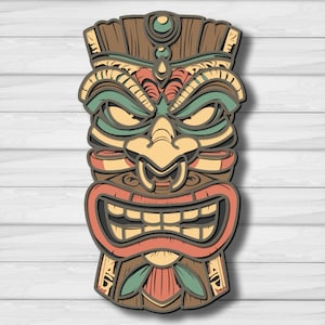 May include: A multi-layered wooden wall art piece shaped like a tiki mask. The design features a stylized face with a prominent nose, bared teeth, and deep-set eyes. The layers are colored in shades of brown, muted red, cream, and sage green.