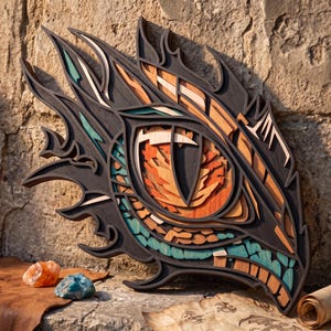 May include: A multi-layered wooden wall art piece depicting a stylized dragon eye. The design features intricate cutouts in black, orange, teal, and natural wood tones, creating a dimensional effect with sharp, flame-like edges surrounding the central iris.