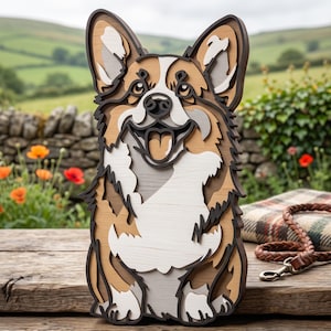 Könnte beinhalten: Ein mehrschichtiges Wandkunstobjekt aus Holz in Form eines Corgi-Hundes. Das Design besteht aus gestapelten Ausschnitten in den Farben Hellbraun, Weiß, Dunkelbraun und Grau, die ein dreidimensionales Porträt des Hundes mit offenem Maul und Zunge zeigen.
