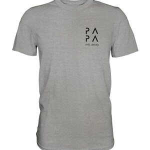May include: A heather gray t-shirt with a black graphic of the letters "PA" stacked on top of each other, with the text "est. 2023" below.