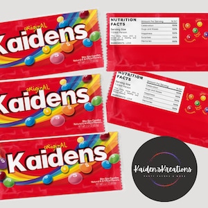 May include: Three red and white candy bags with the text "original Kaidens" printed in black. The bags are filled with colorful candies and have a rainbow design. The bags also have a nutrition facts label with a QR code that says "SCAN ME".