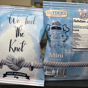 May include: Two blue and white snack bags with the text "We Tied The Knot" and "Just Married". One bag features a rope knot design, the other has a car graphic and "Nutrition Facts" with "Love" at 1000.