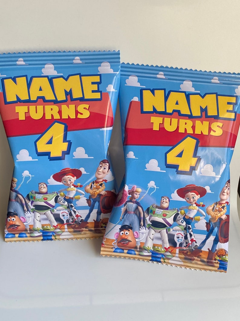 Puede incluir: Dos bolsas de fiesta azules y rojas con tem&aacute;tica de Toy Story. Las bolsas muestran el texto "NAME TURNS 4" e im&aacute;genes de Woody, Buzz Lightyear, Jessie y otros personajes de la pel&iacute;cula.