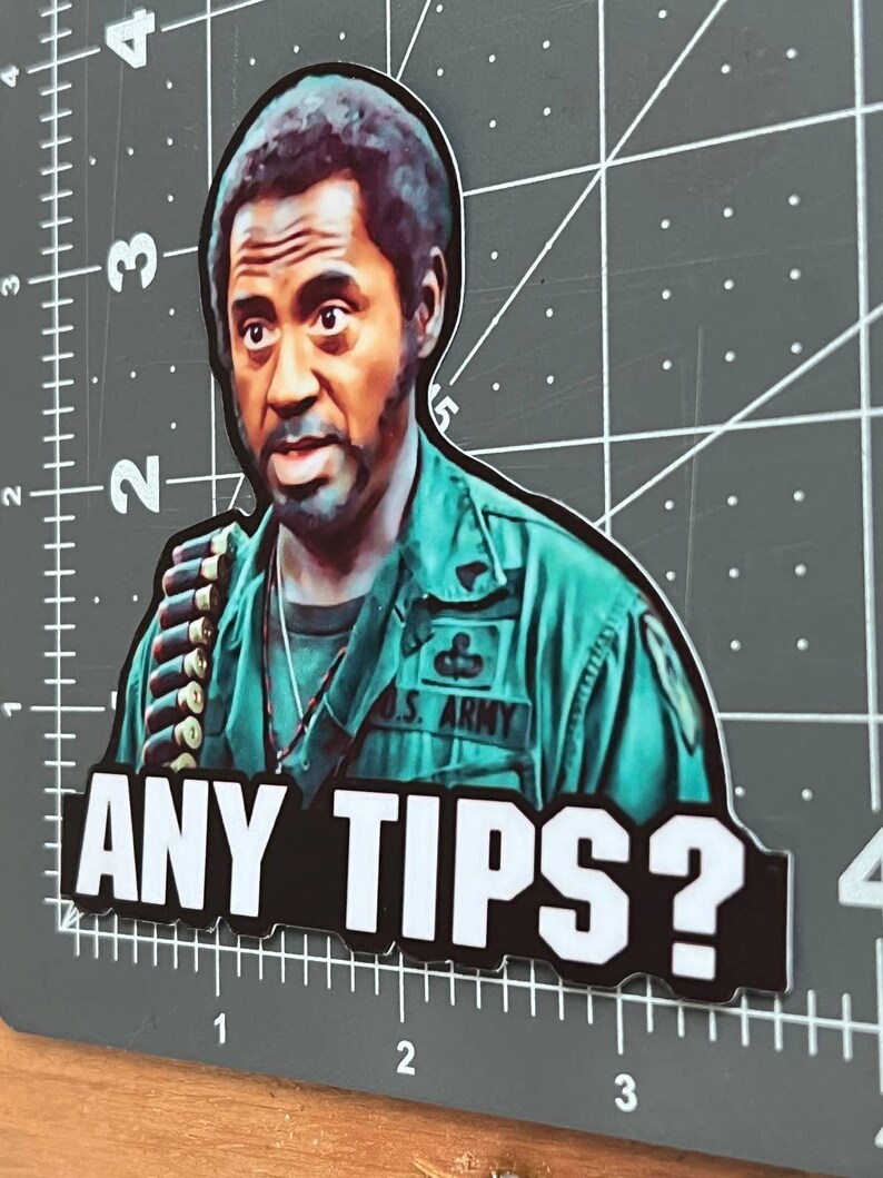 May include: A sticker featuring a man in a green military uniform with the text "U.S. ARMY" on his chest. He is looking at the camera with a questioning expression. The text "ANY TIPS?" is printed in white letters on a black background.
