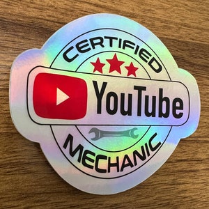 May include: A holographic sticker with the text "CERTIFIED YouTube MECHANIC" in a circle with three red stars and a red YouTube logo with a play button.