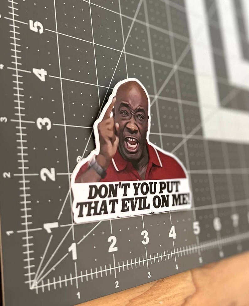 May include: A sticker featuring a close-up of a man with a serious expression, pointing his finger and saying "DON'T YOU PUT THAT EVIL ON ME!"