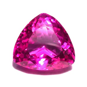 May include: A vibrant pink gemstone with a triangular cut and a high polish. The gemstone is faceted and reflects light.