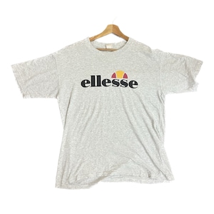 May include: A gray short-sleeved t-shirt with the word "ellesse" printed in black letters and a red, yellow, and white logo.