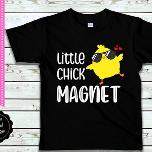 May include: Black t-shirt with a white graphic of a yellow chick wearing sunglasses and the text "little chick magnet".