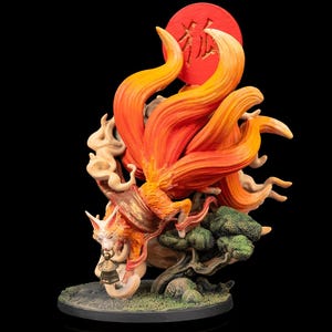 Könnte beinhalten: Detaillierte Figur eines mythischen Fuchses mit neun feurigen orangefarbenen Schwänzen, vor einer roten Sonne mit japanischen Schriftzeichen. Der Fuchs ist mit einer Glocke dargestellt und von stilisierten Wolken und einem kleinen Baum umgeben, alles auf einem kreisförmigen Sockel.
