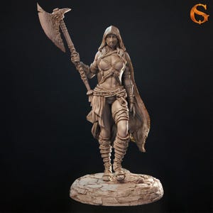 May include: A detailed figurine of a warrior woman in a hooded cloak, holding a large axe. The figure is clad in armor and wrapped cloth, standing on a stone base. The color is a light brown.