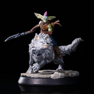 May include: A miniature figurine of a goblin riding a white wolf. The goblin has green skin, a pink mohawk, and is armed with a sword. The wolf has gray fur and blue eyes. The figurine is on a black base.