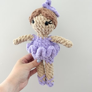 May include: A crocheted doll with brown hair, a purple dress, and purple ballet shoes.