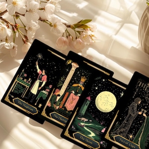 May include: Four tarot cards with black backgrounds and gold borders are displayed. The cards feature illustrations of The Magician, The Hierophant, The Moon, and Two of Cups. White flowers and a vase are in the background.