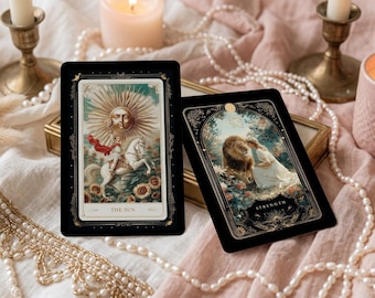 May include: Two tarot cards with black borders are displayed on a soft, textured surface. One card features a sun with a face, the other shows a woman with a lion. The cards are surrounded by candles, pearls, and dried flowers.