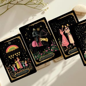 May include: Four tarot cards with black backgrounds and gold borders are displayed. The cards feature illustrations of a rainbow, a knight on horseback, two women toasting, and a queen. The cards are arranged on a white surface with decorative elements.