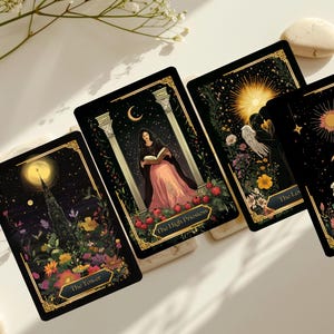 May include: Four tarot cards with black backgrounds and gold borders are displayed. Each card features detailed illustrations with celestial and floral elements. The cards are labeled "The Tower", "The High Priestess", "The Lovers", and "The Fool".