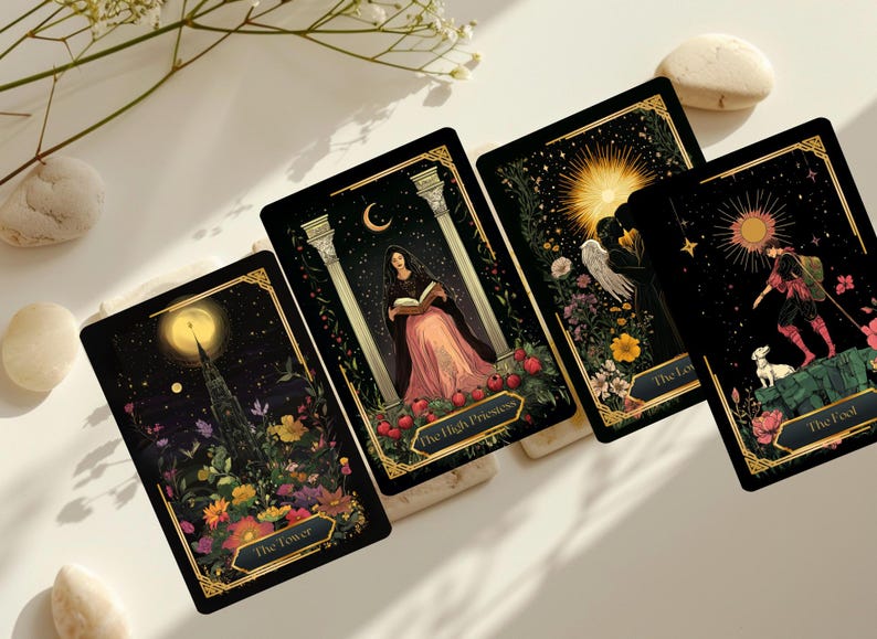 May include: Four tarot cards with black backgrounds and gold borders are displayed. Each card features detailed illustrations with celestial and floral elements. The cards are labeled "The Tower", "The High Priestess", "The Lovers", and "The Fool".