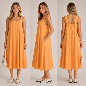 May include: An orange midi dress with a square neckline and a relaxed fit. The dress is sleeveless and falls to the mid-calf. The model is wearing white loafers and carrying a white purse. The dress has pockets.