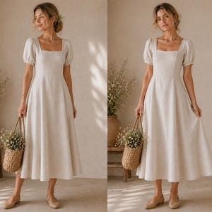 May include: A beige midi dress featuring a square neckline, short puff sleeves, and a fitted bodice that transitions into a flared skirt. The dress is made of a textured fabric and is paired with a woven straw basket filled with small white flowers.