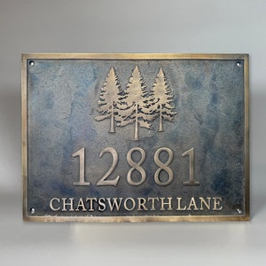 Puede incluir: Una placa de dirección rectangular de metal color bronce con un relieve de tres pinos sobre el número de casa 12881 y el texto CHATSWORTH LANE. La placa tiene un acabado oscuro texturizado, bordes pulidos y cuatro orificios en las esquinas.
