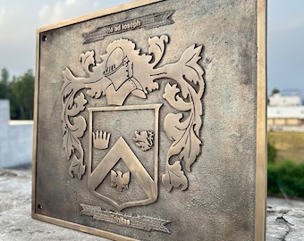 May include: A rectangular bronze-toned metal plaque featuring a raised coat of arms with a helmet, a chevron, a crown, a lion, and an eagle. The text "Ite ad Ioseph" is engraved at the top and "Trinitas" at the bottom. It has four corner mounting holes.