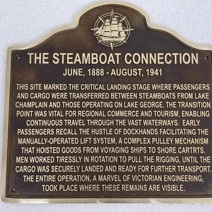 Puede incluir: Una placa rectangular de bronce con la parte superior redondeada que presenta un emblema en relieve de un barco de vapor y una br&uacute;jula. El texto dice THE STEAMBOAT CONNECTION, JUNE, 1888 - AUGUST, 1941, seguido de una descripci&oacute;n hist&oacute;rica.