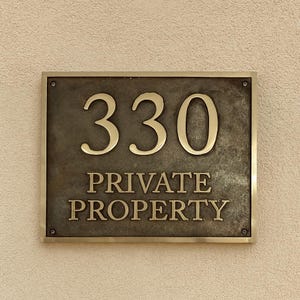 May include: A rectangular metal sign with a dark, weathered bronze finish and a polished gold-toned border. The sign features the number 330 in large, raised gold-toned numerals above the text PRIVATE PROPERTY in matching gold-toned lettering.
