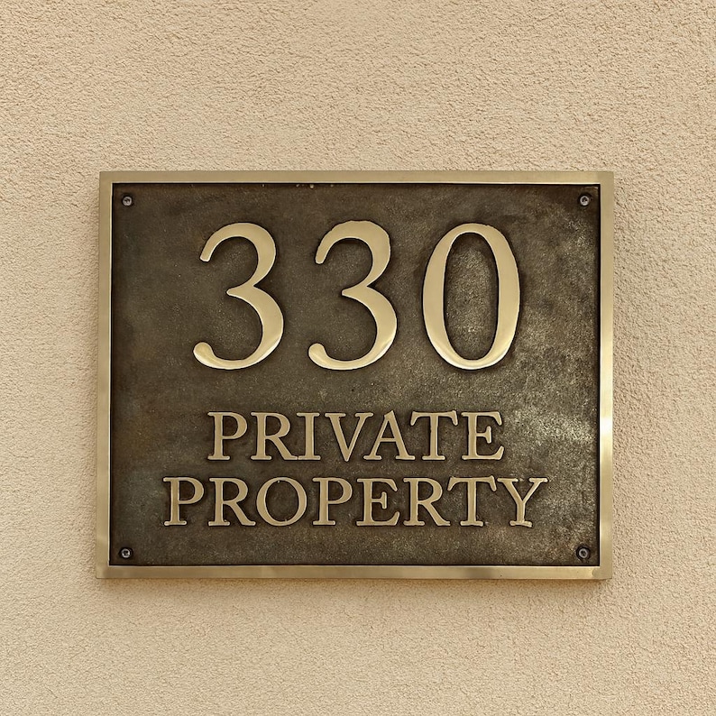 May include: A rectangular metal sign with a dark, weathered bronze finish and a polished gold-toned border. The sign features the number 330 in large, raised gold-toned numerals above the text PRIVATE PROPERTY in matching gold-toned lettering.