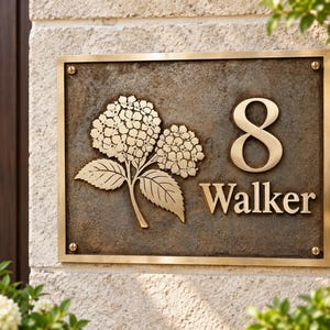 May include: A rectangular bronze house plaque featuring a raised brass number 8 and the name Walker in a serif font. The plaque includes a detailed relief of two hydrangea flower clusters with leaves, secured by four brass corner screws.