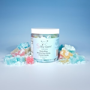 May include: A clear jar of Silky Gem Crystal Candy, with a white lid, sits among colorful, crystal-shaped candies. The jar's label reads "Sizzle Bites Xtreme Sour Sticky Crystal Candy" and the net weight is 8.75 oz (240g). The candies are pink, blue, and yellow.