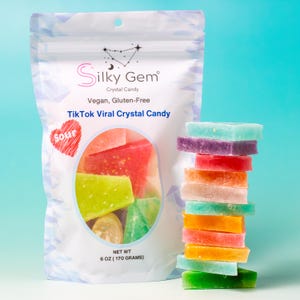 May include: A bag of Silky Gem crystal candy with a variety of colors, including green, red, and purple. The bag is labeled "TikTok Viral Crystal Candy" and "Vegan, Gluten-Free." A stack of colorful crystal candies is next to the bag.