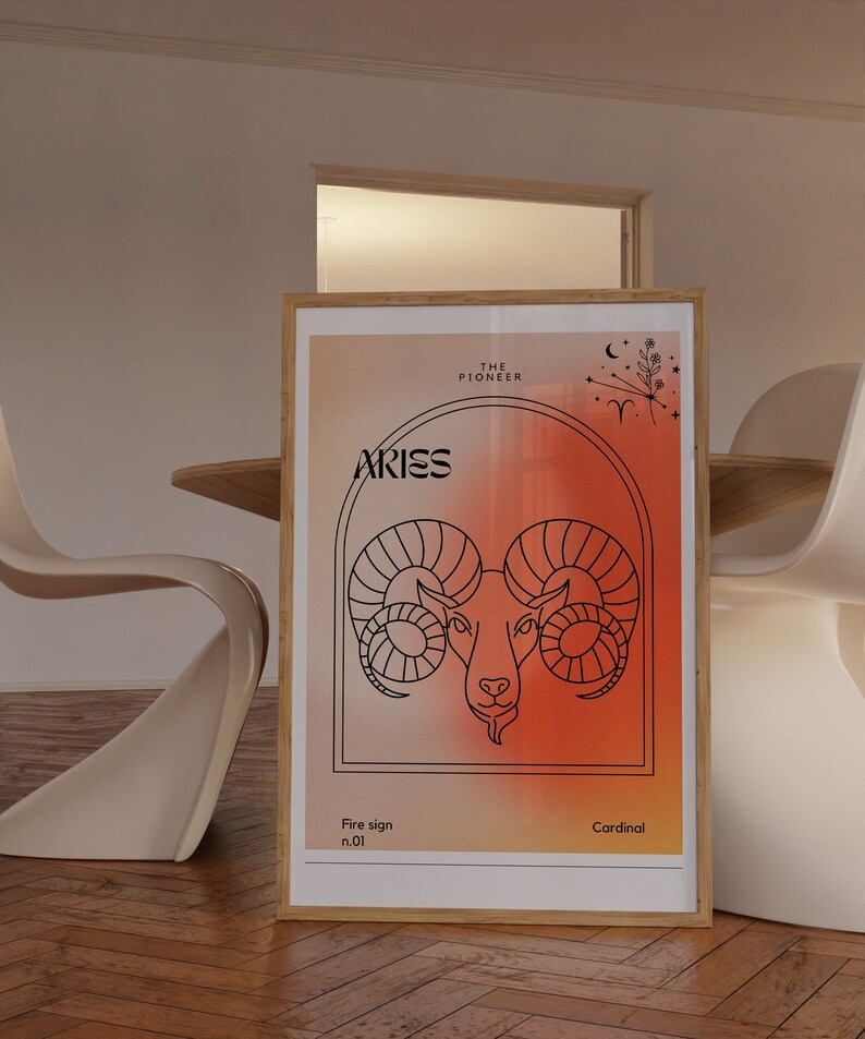 May include: A framed print with a red and orange gradient background. The print features a black line drawing of an Aries zodiac sign, with the text "Aries" and "The Pioneer" above the image. The text "Fire sign n.01" and "Cardinal" are below the image.
