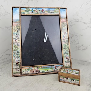 May include: A rectangular picture frame and a small matching rectangular box, both featuring a gold-toned finish and decorative panels depicting a colorful hunting scene with riders on horseback, dogs, and trees in a landscape setting.