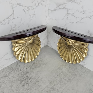 May include: A set of three ceramic mugs with a speckled, matte finish. The mugs are in shades of cream, light brown, and dark brown. Each mug has a simple, minimalist design and a rounded handle.