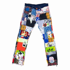 Puede incluir: Un par de pantalones vaqueros azules con un diseño de patchwork. Los parches están hechos de diferentes telas y presentan varios colores, patrones e imágenes, incluyendo un personaje de dibujos animados, un gato y una bandera japonesa.