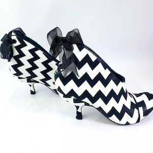 May include: Black and white chevron patterned heeled ankle boots with a black ribbon bow on the top of the boot.