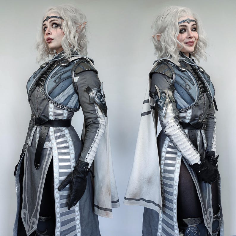 May include: Two figures in fantasy-inspired costumes, both wearing white and grey armor with intricate details. They have long white hair and pointed ears. The figures are posed in a symmetrical fashion, with one facing left and the other facing right.