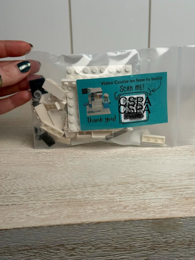 May include: A clear plastic bag containing white and black building blocks and a teal card. The card reads "Video Course on how to build SCAN ME!" with a QR code and the words "Thank you!"