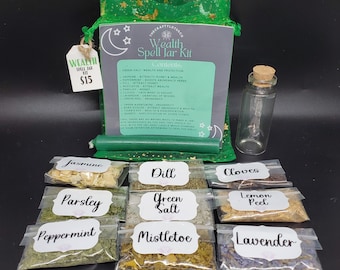 May include: A green drawstring bag with a label that reads "Wealth Spell Jar Kit" and lists the contents of the kit. The kit includes a small glass jar, crystals, and various herbs and spices in individual clear plastic bags labeled with their names: Jasmine, Dill, Cloves, Parsley, Green Salt, Lemon Peel, Peppermint, Mistletoe, and Lavender.