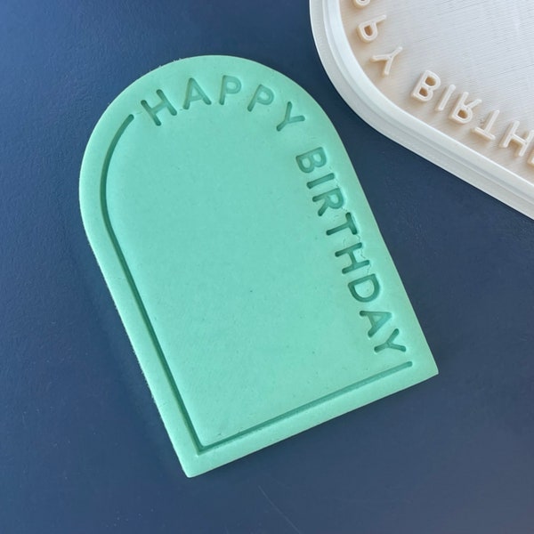 May include: A green arch-shaped cookie cutter with the text "HAPPY BIRTHDAY" embossed around the edge.
