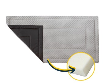 May include: A gray and black quilted play mat with a white foam insert. The mat is designed for babies and toddlers.