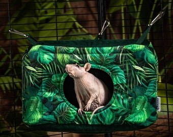 May include: A green and white hanging hammock with a tropical leaf print. A hairless rat is peeking out of the opening of the hammock.
