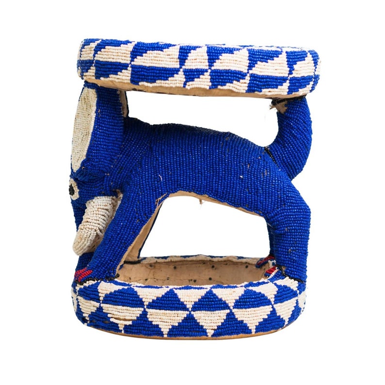 May include: A blue beaded stool shaped like an elephant. The stool has a round top and a base with a geometric pattern.