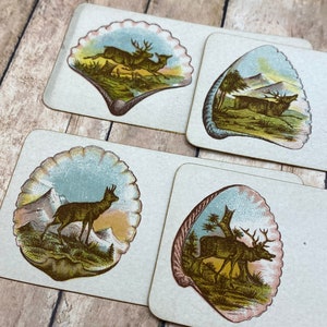 May include: Four vintage playing cards with a seashell design. Each card features a different illustration of a deer or elk in a woodland setting. The cards are printed on thick paper with a textured surface.