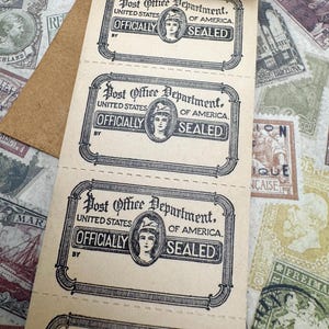 May include: A roll of vintage paper labels, each with the text "Post Office Department, United States of America, Officially Sealed." The labels have decorative borders and a central portrait of a woman. The background shows other vintage stamps.