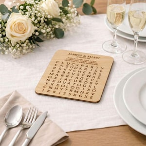A wooden coaster with a crossword puzzle on it, placed on a table with a floral arrangement, wine glasses, and silverware.