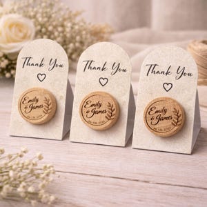 Three wooden nameplate magnets with the names 'Emilly & James' engraved on them, placed on a wooden surface.